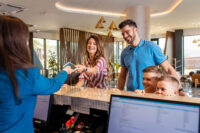 Smiling family of four in the hotel lobby check in at the reception for vacation