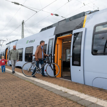 Fahrgast mit Fahrrad steigt ebenerdig in den Zug am Bahnsteig ein