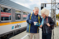 Reisende stehen vor dem alex Zug auf dem Bahnsteig