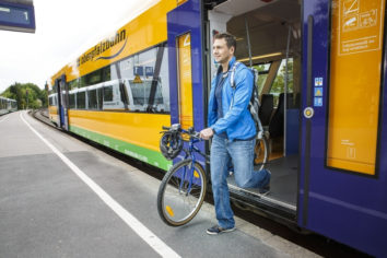 Auf dem Bild sieht man einen Mann, der mit seinem Fahrrad aus der Oberpfalzbahn aussteigt.