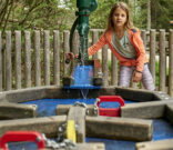 am Wasserspiel im Tierpark Lohberg spielendes Mädchen