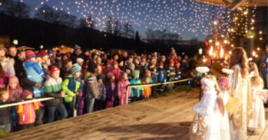 Auftritt von Kindern, die als Engel verkleidet sind auf eine weihnachtlich beleuchteten Bühne