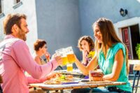 Menschen im Biergarten stoßen mit dem Bier an. Essen auf dem Tisch