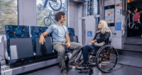 Eine Frau im Rollstuhl ist auf den dafür vorgesehenen Stellplatz im Zug.