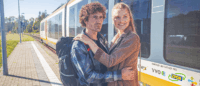 Ein Paar umarmt sich am Bahnsteig.