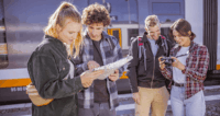 Eine Gruppe von Personen schaut in eine Wanderkarte und in eine Kamera am Bahnhof.