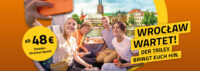 Gruppe sitzt im Zug trilex und macht ein Foto von sich, im Hintergrund sieht man die Stadt Breslau und einen Hinweis auf das Ticket