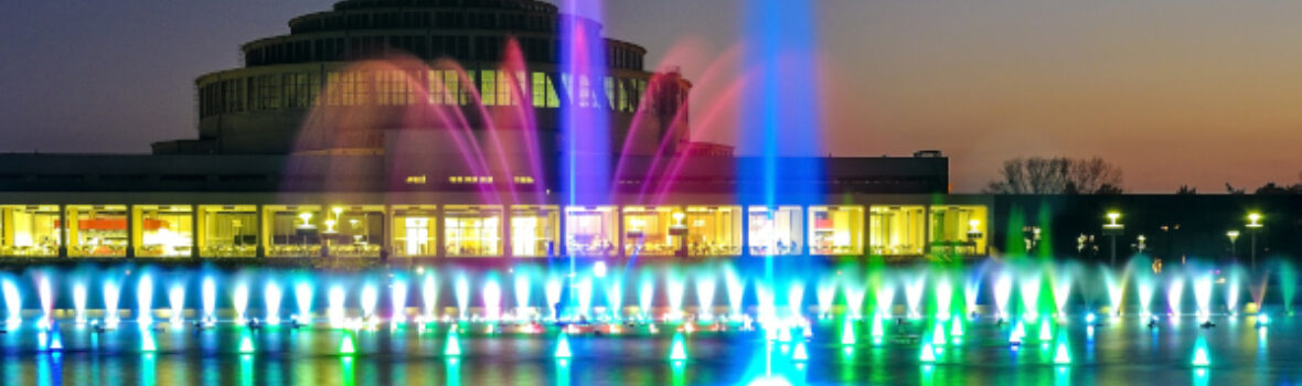 Farbige Wasserfontänen vor der beleuchteten Jahrhunderthalle