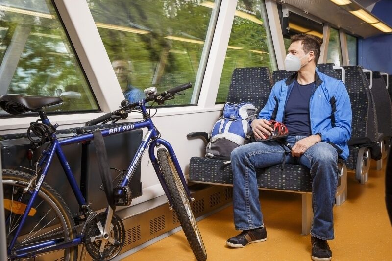 Person sitzt im zug mit einem fahrrad FFP2 V1