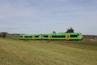 Die waldbahn fährt auf dem Gleis neben einer großen Wiese