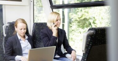 Zwei Pendler fahren mit der Vogtlandbahn, eine Person tippt etwas auf dem Laptop die andere Person telefoniert