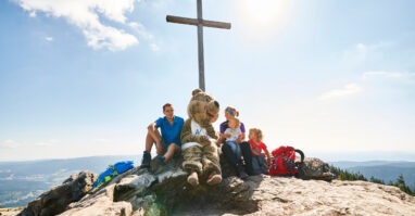 Das Gipfelkreuz am Großen Arber, daherum sitzen Wanderer