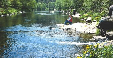 Person die am Ufer des schwarzen Regens in Bayerisch Kanada sitzt