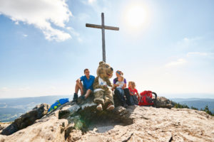 Das Gipfelkreuz am Großen Arber, daherum sitzen Wanderer