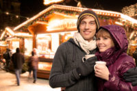 Zwei Menschen die an einem Weihnachtsmarkt sind und eine Tasse in der Hand halten