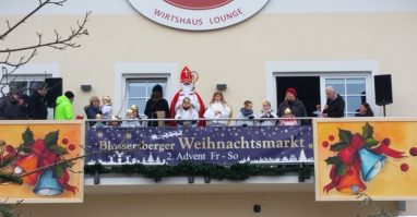 Der Nikolaus steht mit Engel und Krampus am Balkon vom Blossersberger Keller, links und rechts stehen noch ein paar Leute
