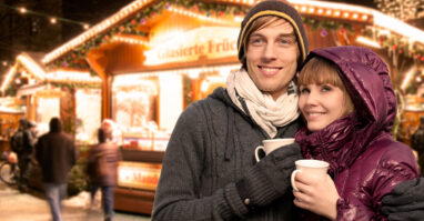 Zwei Menschen die an einem Weihnachtsmarkt sind und eine Tasse in der Hand halten