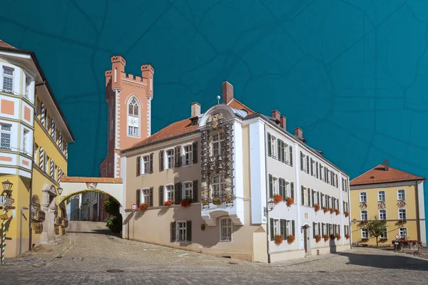 Historische Gebäude mit Uhrturm und Kopfsteinpflasterstraße bei Sonnenschein.