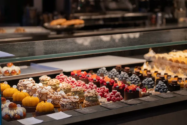 Auslage mit verschiedenen Törtchen, Gebäck und Pralinen in einer Vitrine.