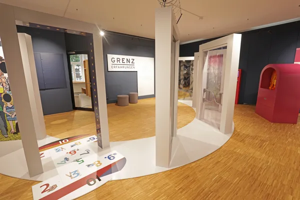 Innenaufnahme des Museums mit modernen Ausstellungsbereichen, weißen Rahmen, bunten Elementen und dem Schriftzug ‚Grenzerfahrungen‘.