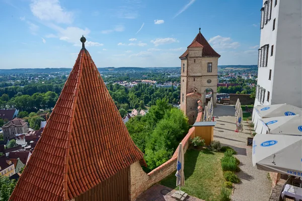 Blick von der Burg Trausnitz auf rote Dächer und die Stadt Landshut, sonniger Tag mit klarem Himmel.