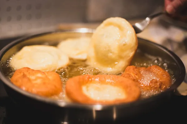 Mehrere goldbraune Kücherl werden in heißem Öl in einer Pfanne ausgebacken.
