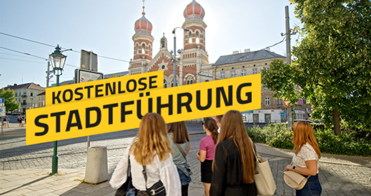 Eine Gruppe von Teilnehmenden steht bei einer Stadtführung auf einem Platz, im Hintergrund die Große Synagoge von Pilsen; darüber der Schriftzug „Kostenlose Stadtführung“.