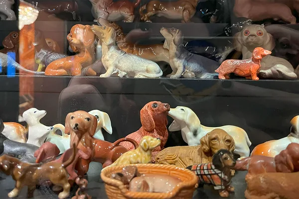 Vitrine mit zahlreichen Dackelfiguren in verschiedenen Farben und Materialien.