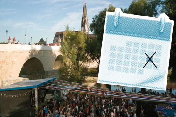 Großveranstaltung unter freiem Himmel an der Steinernen Brücke in Regensburg mit Bühne, Publikum und Blick auf die historische Altstadt.