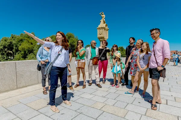 Gruppe von Teilnehmerinnen und Teilnehmern bei einer geführten Stadttour auf der Steinernen Brücke in Regensburg, im Hintergrund die historische Altstadt und eine Brückenfigur.