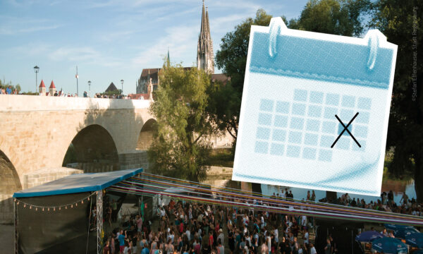 Großveranstaltung unter freiem Himmel an der Steinernen Brücke in Regensburg mit Bühne, Publikum und Blick auf die historische Altstadt.