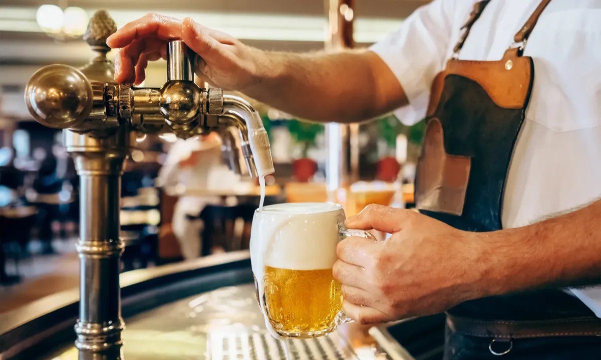 Nahaufnahme eines frisch gezapften Biers in einem traditionellen Pub mit rustikalem Ambiente.