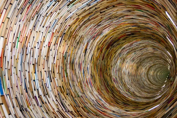 Spiralförmige Installation aus gestapelten Büchern, die einen tiefen Tunnel bildet.