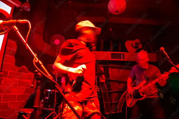 Live-Band spielt auf einer kleinen Bar-Bühne, rotes Licht taucht den Raum in stimmungsvolle Atmosphäre.