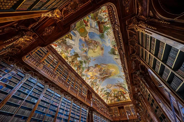 Prunkvolle Bibliothek mit hohen Bücherregalen und kunstvoll bemalter Decke.