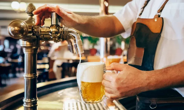 Nahaufnahme eines frisch gezapften Biers in einem traditionellen Pub mit rustikalem Ambiente.