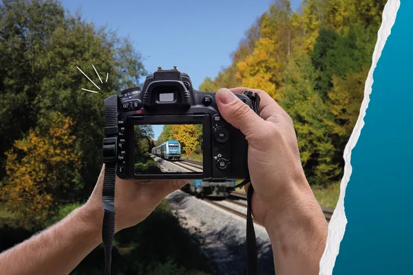 Ein Bild duch eine Kamera. Zu sehen ist der alex-Zug, wie er durch die Herbstlandschaft fährt und dabei fotografiert wird.