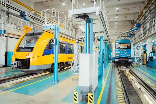 Innenansicht der Werkstatt Schwandorf mit einem gelben oberpfalzbahn-Zug und einem blauen alex-Zug.