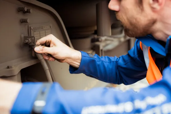 Person in blauer Arbeitskleidung prüft Bauteile am Fahrwerk eines Zuges.
