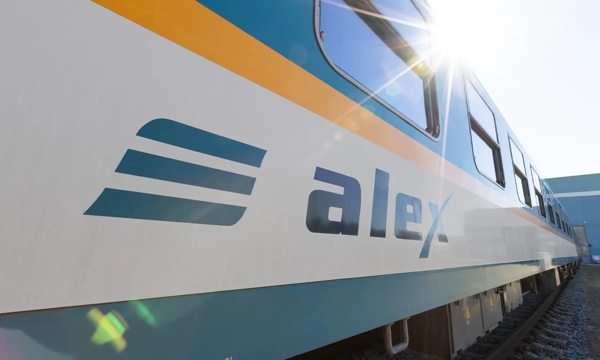 Nahaufnahme eines alex-Zuges mit blau-weißem Design und Sonnenspiegelung auf der Seite.