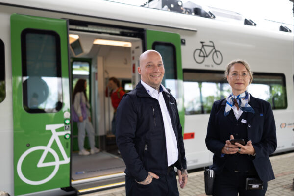 Zwei Mitarbeitende der Länderbahn in Unternehmensbekleidung vor dem Fahrzeug der S-Bahn Mitteldeutschland
