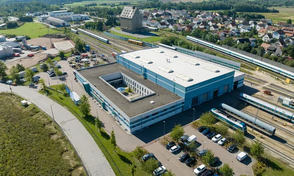 Letecký pohled na velkou dílnu s kolejišti, vlaky a okolní krajinou ve Schwandorfu.