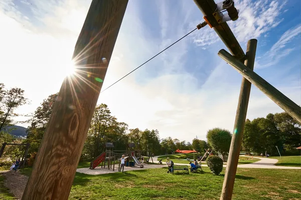 Seil- und Holzelemente eines Kletterspielplatzes auf einer Wiese bei sonnigem Wetter