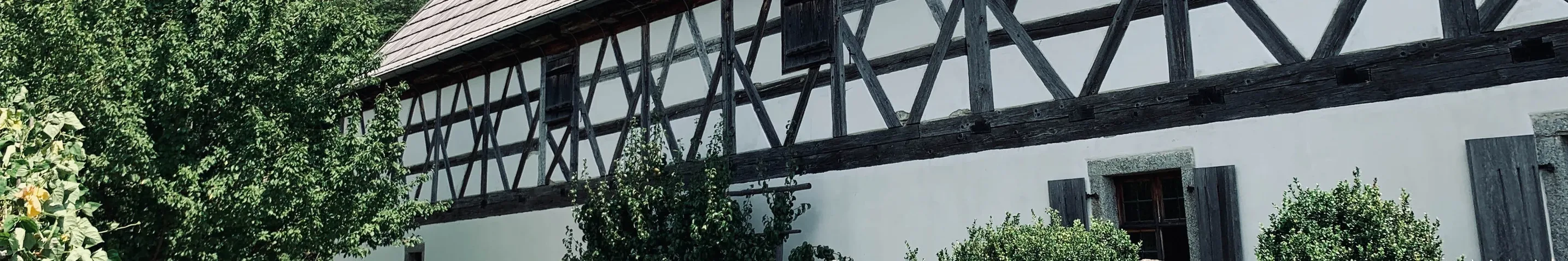 Ausschnitt einer Fachwerkfassade mit Garten im Vordergrund