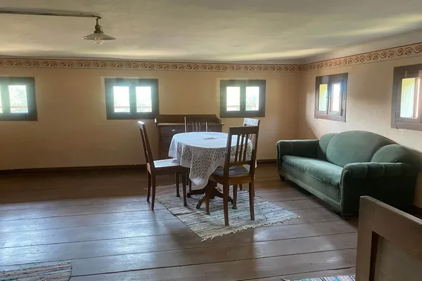 Historischer Wohnraum mit Holzboden, Tisch mit Stühlen und Sofa