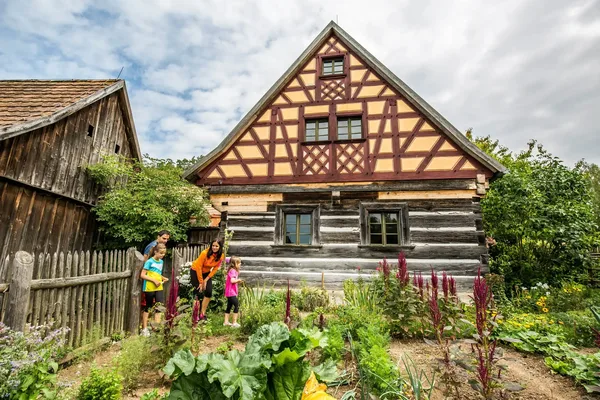 Fachwerkhaus mit Holzfassade und gepflegtem Garten mit einer Familie im Vordergrund