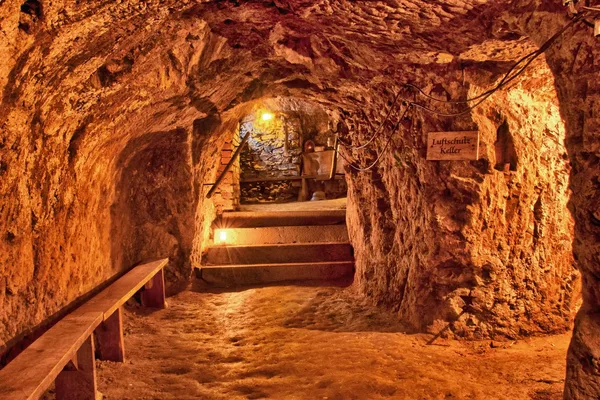 Hell beleuchteter Felsengang mit Sitzgelegenheiten an der Seite