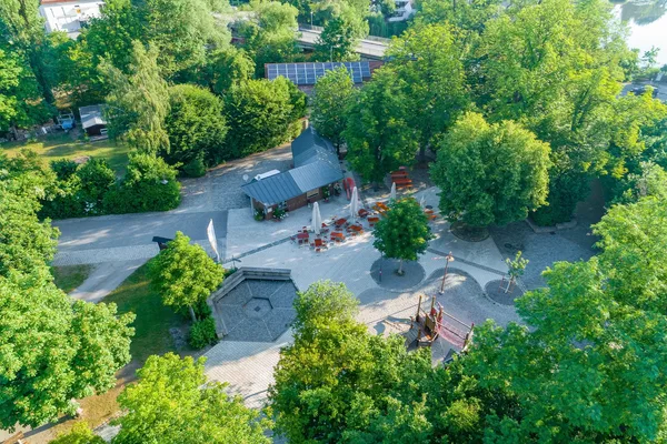 Luftaufnahme einer Parkanlage mit Spielplatz, Wegen und kleinen Gebäuden
