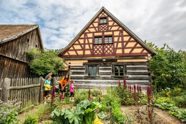Ein altes Fachwerkhaus mit Gemüsegarten, den eine Familie besichtigt.
