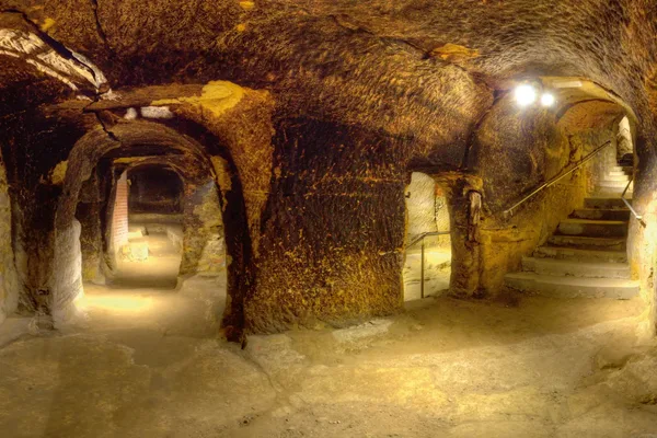 Mehrere Felsengänge mit Beleuchtung und einer Treppe mit Geländer